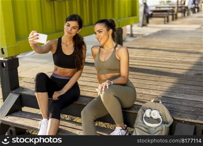 Pretty young women in sportswear taking selfie with mobile phone after exercise training