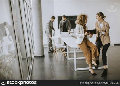 Pretty young women using digital tablet in modern office in front of their team