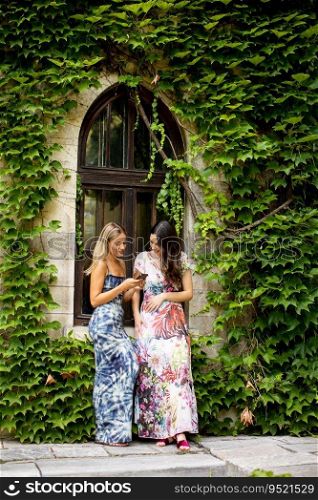 Pretty young women using mobile phone by old house with ivy