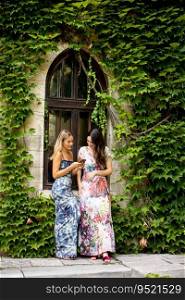 Pretty young women using mobile phone by old house with ivy