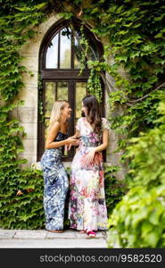 Pretty young women using mobile phone by old house with ivy