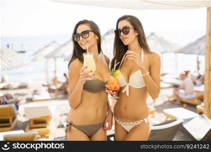 Pretty young women with coctails on the beach