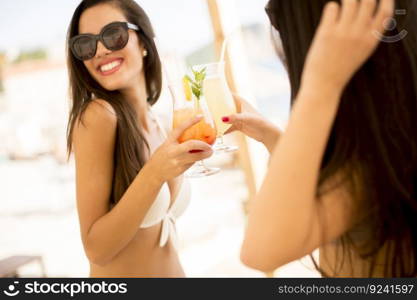Pretty young women with coctails on the beach