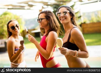 Pretty young women with ice creams by the swimming pool on a sunny summer day