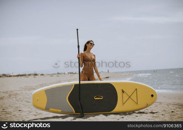 Pretty young women with paddle board on the beach on a summer day