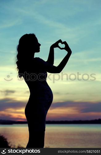 Prgenant mother making the heart sign