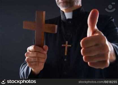 Priest holding cross of wood praying with ok sign finger