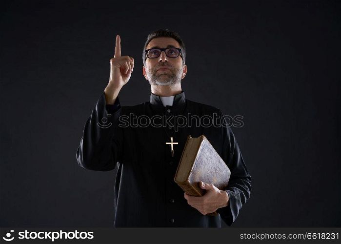 Priest male holding bible pointing finger up to heaven in sky