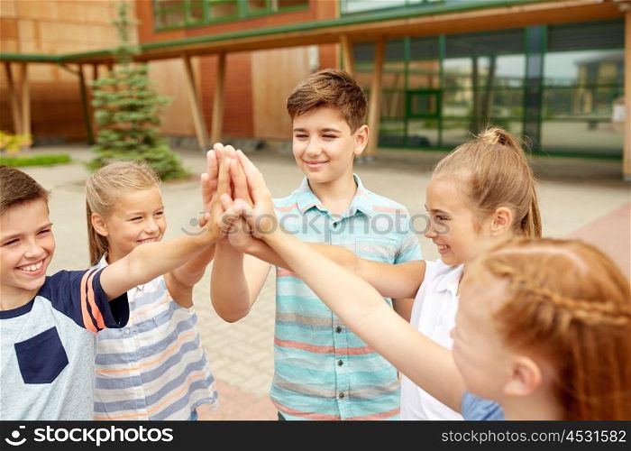 primary education, friendship, childhood and people concept - group of children or students making high five at school yard. group of children making high five at school yard