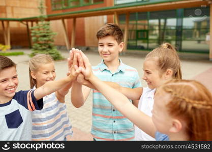 primary education, friendship, childhood and people concept - group of children or students making high five at school yard. group of children making high five at school yard