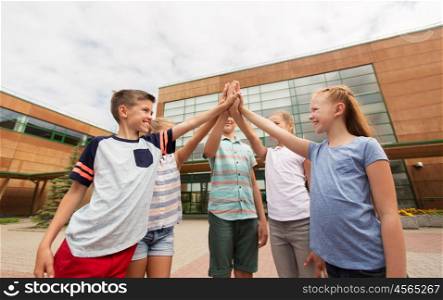 primary education, friendship, childhood and people concept - group of children or students making high five at school yard