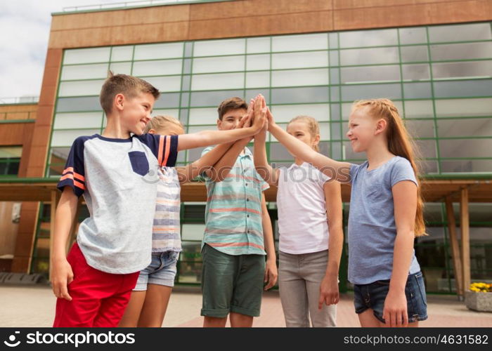 primary education, friendship, childhood and people concept - group of children or students making high five at school yard