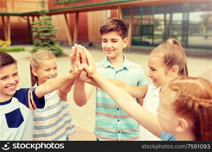 primary education, friendship, childhood and people concept - group of children or students making high five at school yard. group of children making high five at school yard