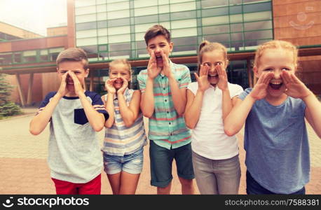 primary education, friendship, childhood and people concept - group of happy children or elementary school students calling or shouting outdoors. group of happy elementary school students