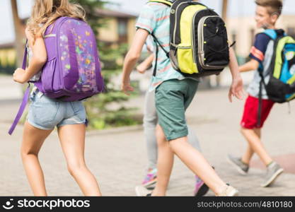 primary education, friendship, childhood and people concept - group of happy elementary school students with backpacks running outdoors