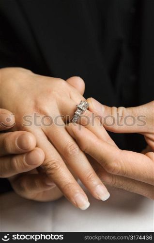 Prime adult Asian male putting engagement ring on female&acute;s hand.