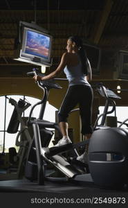 Prime adult Caucasian female on elliptical machine at gym.