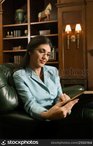 Prime adult Hispanic female sitting and reading.