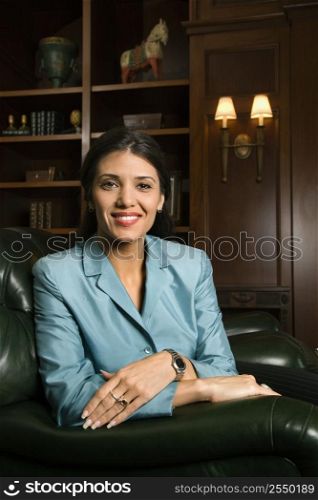 Prime adult Hispanic female sitting looking at viewer smiling.