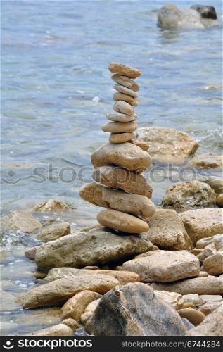 Primitive stone structure on rocky shore. Balanced rocks by the sea water.