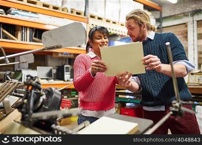 Printer and trainee checking printed paper in traditional print workshop