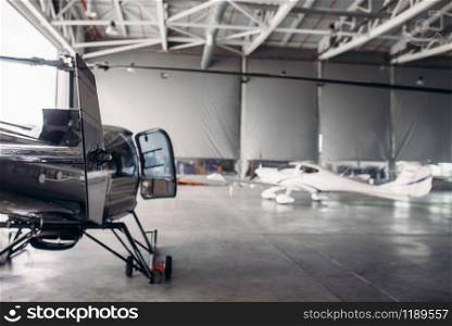Private airline air park in airport hangar, small turboprop airplane and helicopter in aerodrome building, propeller plane and copter, inspection before flight.Business air transportation or aeroclub. Private airline air park in airport hangar