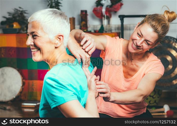 Private yoga instructor with senior woman doing yoga