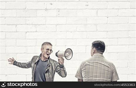Problem of generation conflict. Young man in casual screaming aggressively in megaphone on adult man