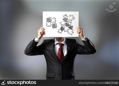 Problem solving. Businessman hiding his face behind paper sheet with sketches