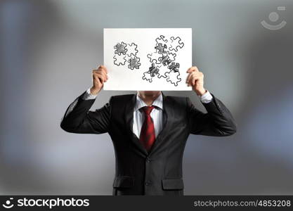 Problem solving. Businessman hiding his face behind paper sheet with sketches