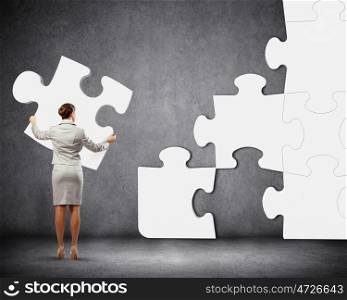 Problem solving. Image of businesswoman connecting elements of white puzzle