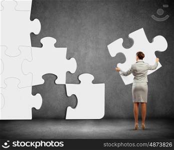 Problem solving. Image of businesswoman connecting elements of white puzzle