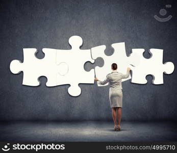 Problem solving. Image of businesswoman connecting elements of white puzzle