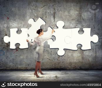 Problem solving. Image of businesswoman connecting elements of white puzzle