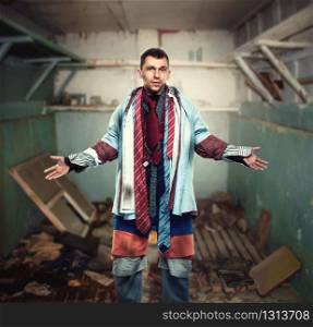 Problems with dressing, lack of money for clothes. Man trying on various shirts, ties, pants and shorts, grunge house on background