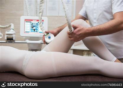 Procedure laser lipolysis of the woman hips in a beauty center.. Procedure laser lipolysis