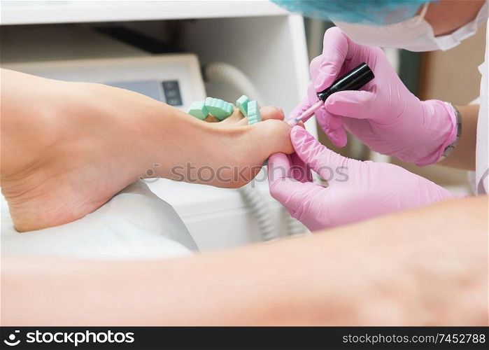 Procedure of pedicure in beauty salon. Nail polishing with nail polish. Closeup photo. Procedure of pedicure in beauty salon