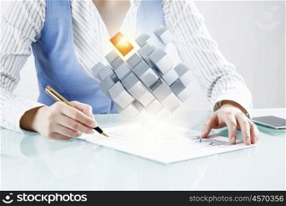 Process of new technologies intergration . Close up of business person writing with pen and digital cube figure on papers