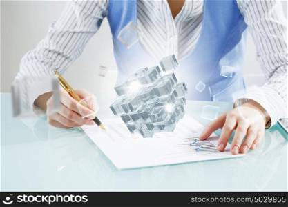 Process of new technologies intergration . Close up of business person writing with pen and digital cube figure on papers