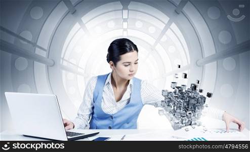 Process of new technologies intergration . Young smiling businesswoman working with laptop and digital levitating cube