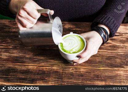 Process of pouring milk in matcha tea cup. Process of pouring milk in matcha tea cup for make latte art. Close up hands