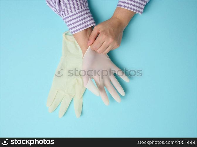 process of putting white latex gloves on hand on blue background, hygiene protector
