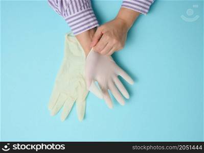 process of putting white latex gloves on hand on blue background, hygiene protector