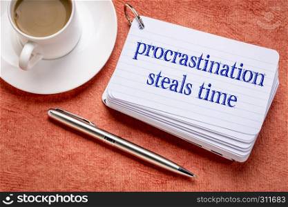 procrastination steals time reminder on a stack of index cards with a cup of coffee