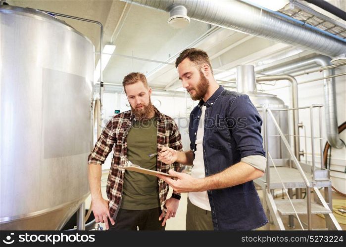 production, business and people concept - men with clipboard at brewery or non-alcoholic beer plant. men with clipboard at brewery or beer plant