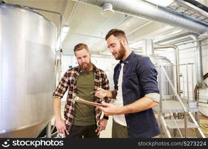 production, business and people concept - men with clipboard at brewery or non-alcoholic beer plant. men with clipboard at brewery or beer plant