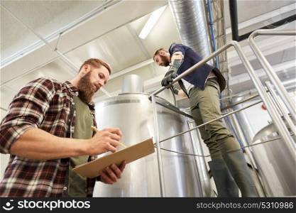 production, business and people concept - men with clipboard working at brewery or non-alcoholic beer plant. men with clipboard at brewery or beer plant kettle
