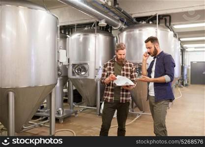 production, business and people concept - men with clipboard working at craft brewery or non-alcoholic beer plant and calling on smartphone. men working at craft brewery or beer plant