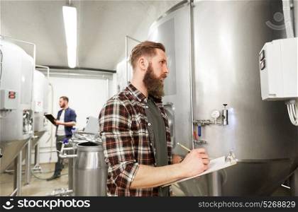 production, business and people concept - men with clipboards working at craft brewery or non-alcoholic beer plant. men with clipboard at craft brewery or beer plant