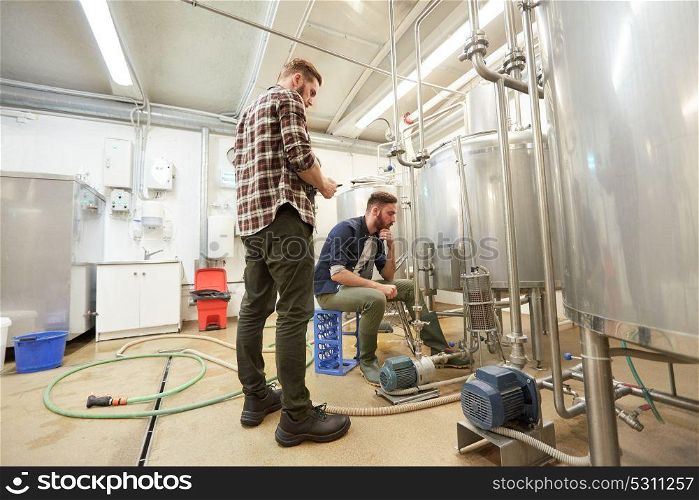 production, business and people concept - men with tablet pc computer and filter compressor at craft beer brewery or non-alcoholic beverage plant. men with tablet pc at craft beer brewery filter